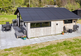 Udendørsbillede af et moderne sommerhus i Løgstør, Danmark, med terrasse og havemøbler.