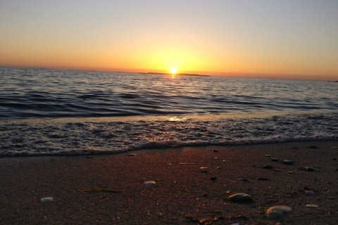 Zonsondergang boven zee vanaf het strand bij 4 star holiday home in Løgstør, Denemarken, met kalme golven.