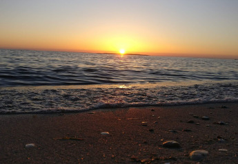 Coucher de soleil sur la mer vu de la plage à 4 star holiday home in Løgstør, Danemark, avec des vagues calmes.