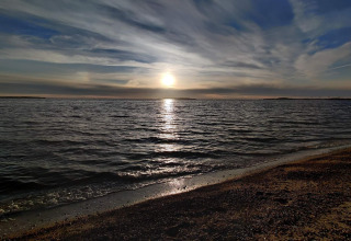 Tramonto sul mare visto dalla spiaggia presso una casa vacanze 4 stelle a Løgstør, Danimarca, onde calme.