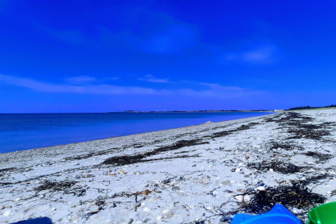 Ruhiger Sandstrand mit blauem Himmel und Meer nahe dem 4-Sterne-Ferienhaus in Løgstør, Dänemark.