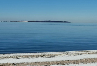 Udsigt over stille hav med en ø i det fjerne, set fra stranden ved 4 star holiday home i Løgstør, Danmark.