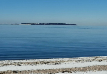Vista al mar tranquilo con una isla lejana desde la playa en 4 star holiday home en Løgstør, Dinamarca.