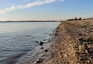Strandbillede ved 4-stjernet feriehus i Løgstør, Danmark, med roligt vand og himmel ved solnedgang.