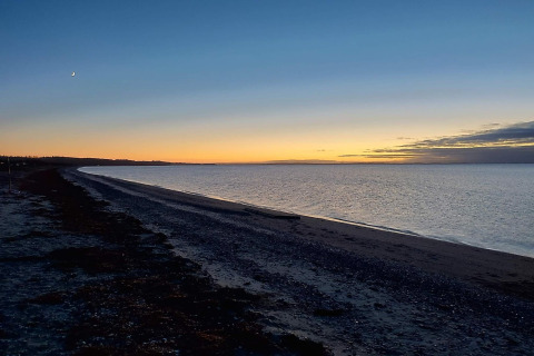 Tramonto sulla spiaggia vicino alla casa vacanze 4 stelle a Løgstør, Danimarca, con cielo limpido.