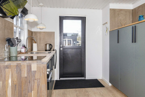 Cucina moderna in una casa vacanze 4 stelle a Løgstør, Danimarca, con piano in legno e armadi eleganti.