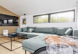 Moderne, heldere woonkamer in een 4-sterren vakantiehuis in Løgstør, Denemarken, met grote zetel.