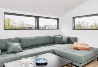 Salon moderne d’une maison de vacances 4 étoiles à Løgstør, Danemark, avec canapé vert et fenêtres.