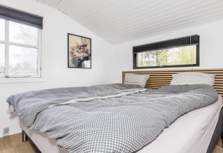 Dormitorio luminoso en una casa de vacaciones en Løgstør, Dinamarca, con cama doble, decoración sencilla y ventanas grandes.