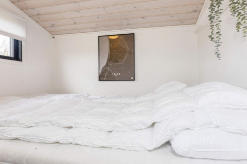 Camera da letto in casa vacanze a 4 stelle a Løgstør, Danimarca, con biancheria bianca e mappa a parete.