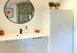 Bagno moderno nella '4 star holiday home in Løgstør', Danimarca, con specchio tondo e mobile chiaro.