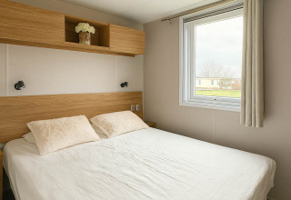 Slaapkamer in Holiday home (PL. 94) bij Camping Papillon in België met tweepersoonsbed en groot raam.