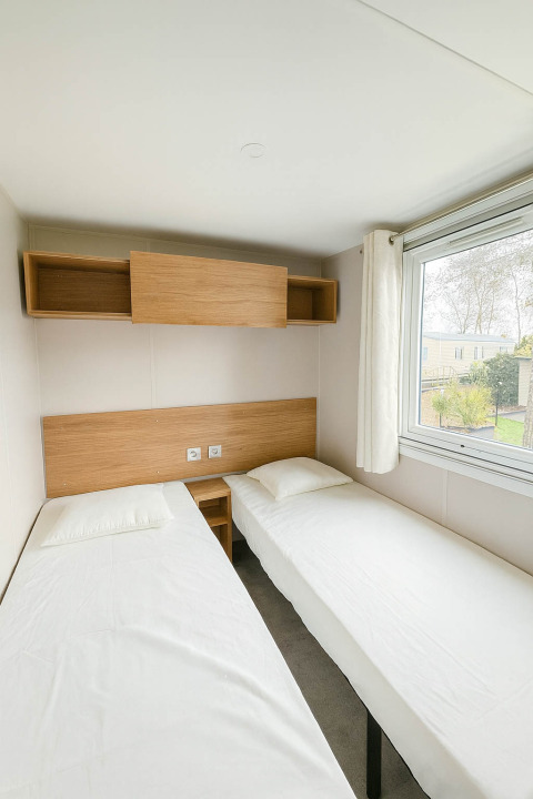 Slaapkamer in Holiday home (PL. 94) op Camping Papillon, België, met twee eenpersoonsbedden en groot raam.