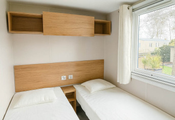 Camera da letto in Holiday home (PL. 94) al Camping Papillon, Belgio, con due letti singoli e grande finestra.