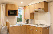 Cocina moderna con muebles de madera, fogón a gas y microondas en lodge de Camping Papillon, Bélgica.