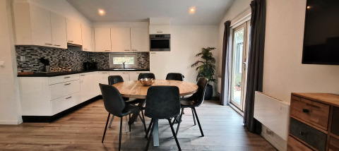 Modern kitchen and dining area at Hackfort Lodge in Kaatsheuvel, Netherlands, with round table and windows.