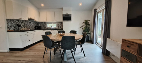 Moderne keuken en eetruimte in Hackfort Lodge, Kaatsheuvel, Nederland, met rond eet- en grote raampartijen.