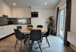 Moderne keuken en eetruimte in Hackfort Lodge, Kaatsheuvel, Nederland, met rond eet- en grote raampartijen.