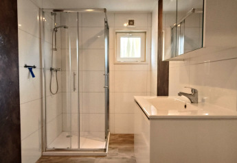 Moderne badkamer in Hackfort Lodge te Kaatsheuvel, Nederland, met douchecabine en wit wastafelmeubel.