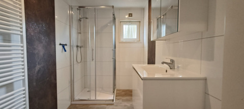 Moderne badkamer in Hackfort Lodge in Kaatsheuvel, Nederland, met een douche en wit badkamermeubel.