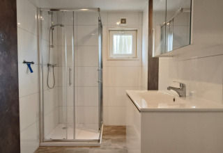Moderne badkamer in Hackfort Lodge in Kaatsheuvel, Nederland, met een douche en wit badkamermeubel.