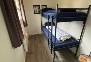 Chambre étroite du Hackfort Lodge à Kaatsheuvel avec lits superposés, sol en bois et petite table.