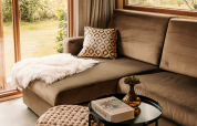 Cozy living room with sectional sofa, patterned pillow, and fluffy throw at Klapkot cabin, De Achterste Hoef.