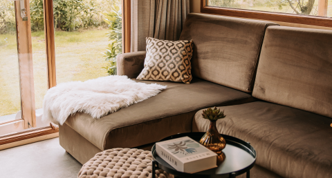 Cozy living room with sectional sofa, patterned pillow, and fluffy throw at Klapkot cabin, De Achterste Hoef.