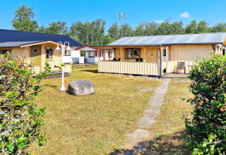Casa vacanze a Skummeslövsstrand, Svezia, con casette gialle, prato e cielo azzurro e soleggiato.