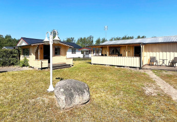 5 person holiday home in Skummeslövsstrand, Sweden, featuring several wooden lodges and a grassy yard.
