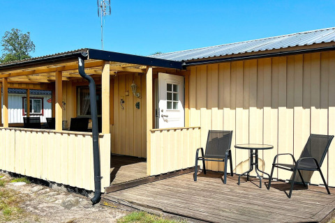 Terrazza soleggiata di una casa vacanze a Skummeslövsstrand, Svezia, con due sedie e un tavolino.
