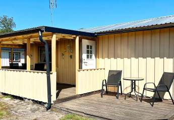 Udendørs terrasse på feriebolig i Skummeslövsstrand, Sverige, med to stole og et lille bord i solskin.
