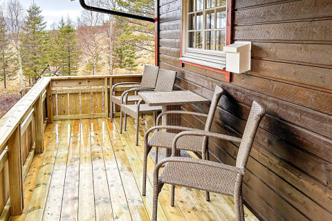 Gemütlicher Balkon am Holzhaus mit Flechtstühlen, Tisch und Waldblick, 4-Personen-Ferienhaus in Lysøysundet.