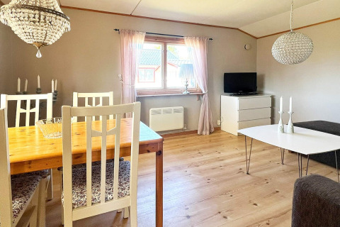 Lyst og hyggeligt opholdsområde i feriehus i Skummeslövsstrand, Sverige, med spiseplads og tv-område.