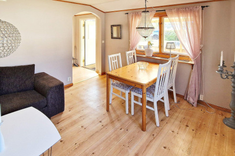Luminoso comedor en casa de vacaciones en Skummeslövsstrand, Suecia, con mesa de madera, cuatro sillas y ventana.