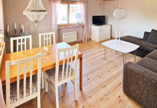 Sala luminosa en casa vacacional en Skummeslövsstrand, Suecia, con mesa de comedor, sofá y televisor.
