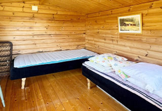 Camera in legno con due letti singoli, pavimento in legno e quadro, in un lodge a Skummeslövsstrand.