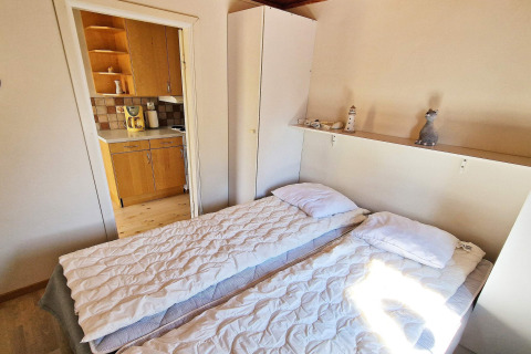 Soveværelse med to enkeltsenge, hvidt skab og udsigt til køkken i feriebolig i Skummeslövsstrand, Sverige.