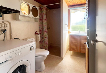 Badkamer met wasmachine, toilet, douche met kleurrijk gordijn en raam in vakantiehuis in Skummeslövsstrand, Zweden.