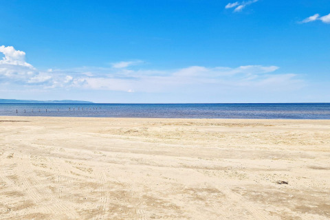 Peaceful sandy beach and sea at ‘5 person holiday home in Skummeslövsstrand’, Sweden, on a sunny day.