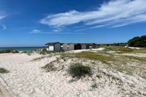 Cabañas de playa en Höllviken, Suecia, sobre dunas de arena cerca del mar y bajo un cielo azul despejado.