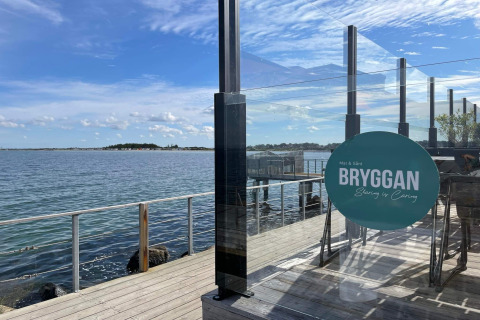Uitzicht over het water vanaf een houten terras met glazen panelen bij Bryggan restaurant in Höllviken.