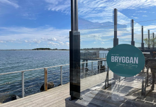 Udsigt over havet fra en træterrasse med glasrækværk ved Bryggan restaurant i Höllviken, Sverige.