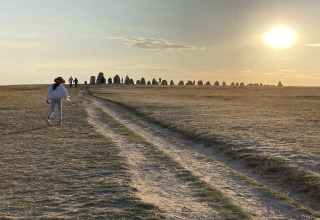 Una persona cammina verso antiche pietre al tramonto vicino a una casa vacanze a 4 stelle a Höllviken, Svezia.