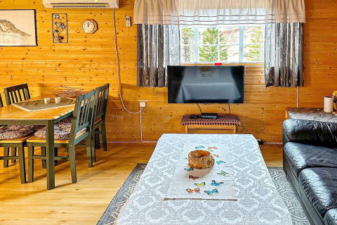 Wohnzimmer eines Ferienhauses in Lysøysundet mit Holzwänden, Esstisch, Sofa und Fensterblick.