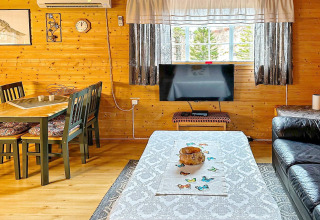 Salon confortable dans une maison de vacances à Lysøysundet avec murs en bois, table et fenêtre donnant sur la nature.
