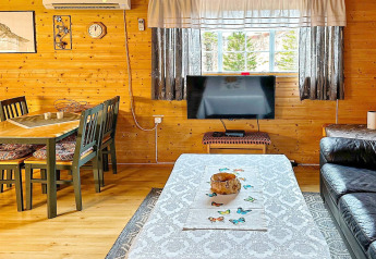Soggiorno accogliente in una casa vacanze a Lysøysundet con pareti in legno, tavolo e finestra panoramica.