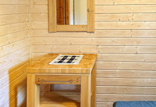 Wooden table and mirror on a paneled wall inside a 4-person holiday yurt in Lysøysundet, Sweden.