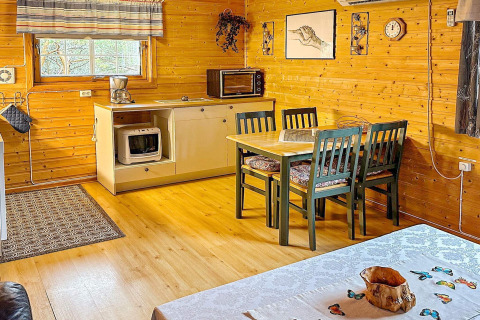 Gemütlicher, holzverkleideter Essbereich in einer Hütte mit Küchenzeile, Esstisch und vier Stühlen.