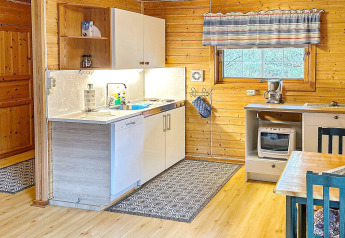 Cuisine chaleureuse dans une maison de vacances en bois avec équipements modernes et rideaux rayés.